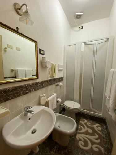a bathroom with a sink and a toilet and a mirror at Hotel Mediterraneo in Cefalù
