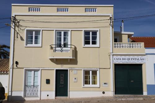 a yellow building with green doors and a balcony at Casa do Quintalão in Raposeira