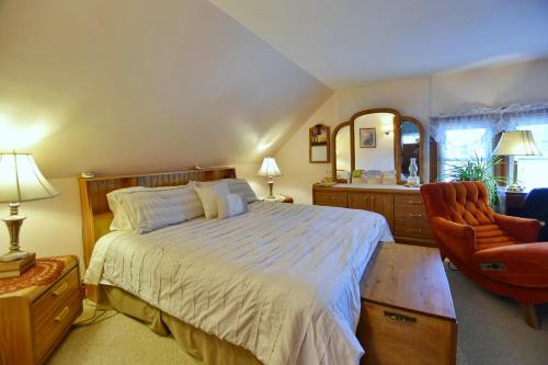 a bedroom with a bed and a chair and a mirror at 10th Avenue Guest House & Suites in Hanover