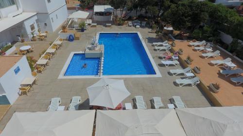 an overhead view of a swimming pool with chairs and umbrellas at Apartamentos San Antonio Beach in San Antonio Bay