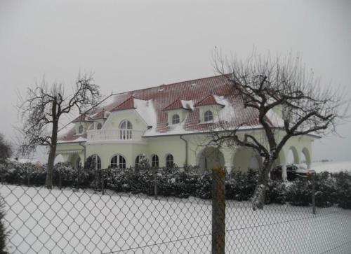 a white house with a red roof behind a fence at Appartement -Villa ROYAL Hélène in Oberlauterbach