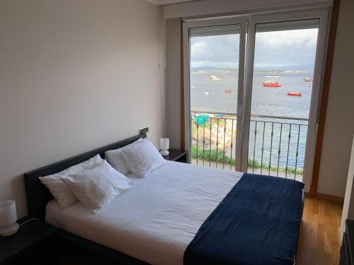 Dormitorio con cama y vistas al agua en Apartamento en la Isla con vistas al Mar, en A Illa de Arousa