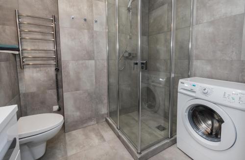 a bathroom with a shower and a washing machine at Relax apartments near Egle in Druskininkai