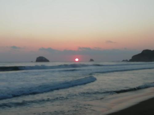 a sunset on a beach with the ocean at HOSTAL CASA DEL ANGEL in Mazunte