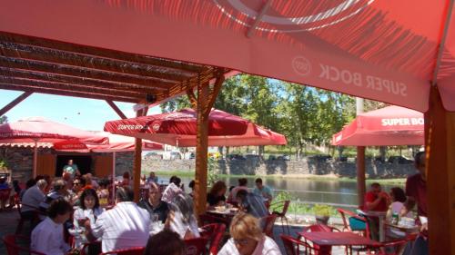 a group of people sitting at tables under red umbrellas at Casa Lerryn in Sertã