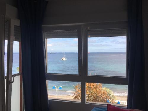 una ventana con vistas al océano con un barco en el agua en Estudio frente al mar en Ceuta