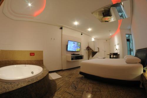 a bedroom with a large bed and a bath tub at Nexos Motel Tamarineira (Adult Only) in Recife