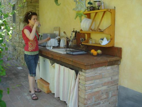 une femme debout dans une cuisine buvant à partir d'un verre dans l'établissement Il Cielo Bio - Il più piccolo B&B del Chianti, à Greve in Chianti
