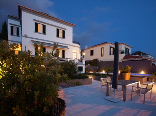 a patio with two chairs and a table in front of a house at Quinta B. in Funchal