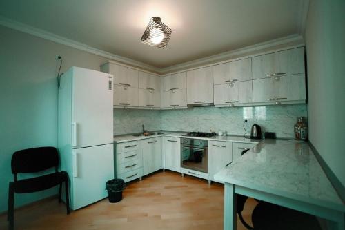 a kitchen with white cabinets and a white refrigerator at Apartment OLD KUTAISI in Kutaisi