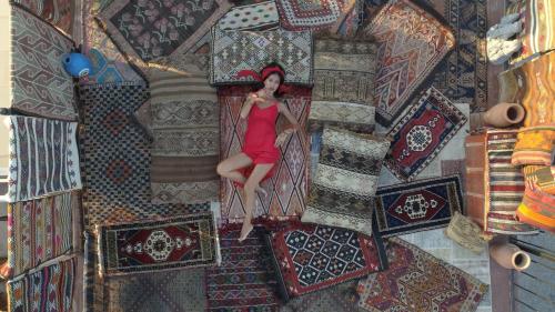 obraz kobiety w czerwonej sukience siedzącej na dywanie w obiekcie Goreme Palace Cave Suites w Göreme