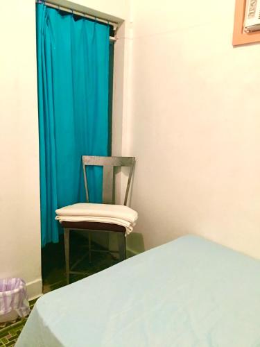 a chair in a room with a blue curtain at MEDUSA'S HOSTEL in Aguadilla