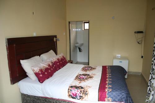 a bedroom with a large bed with white sheets and red pillows at Honeybed Lodge in Lusaka