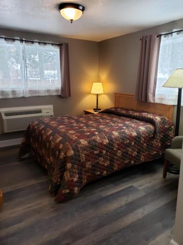a bedroom with a bed and a lamp and windows at Bridge Street Inn in Baker City