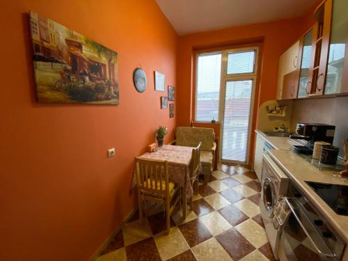 kuchnia z pomarańczowymi ścianami oraz stołem i krzesłami w obiekcie Fantastic 2 Bedroom Apartment - Top Center w mieście Sofia