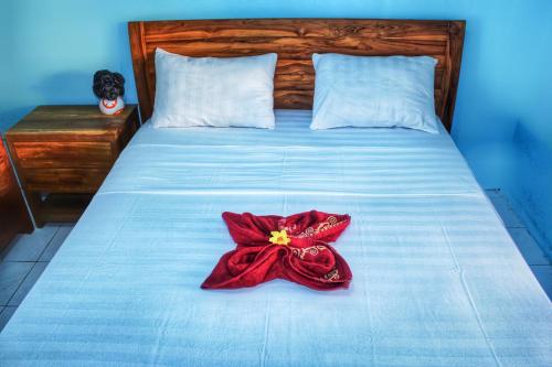 a bed with a red dress on top of it at KJ Purple House Senggigi in Senggigi