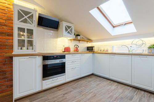 a kitchen with white cabinets and a skylight at Bronowicka Premium Apartment - 52m2 with private parking in Kraków