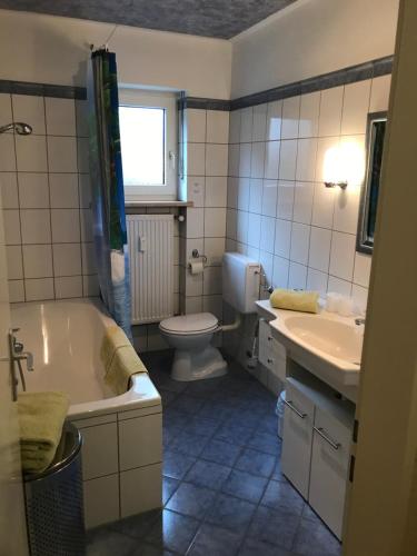 a bathroom with a tub and a toilet and a sink at Gästehaus Ertel - Ferienwohnung in Erding in Erding