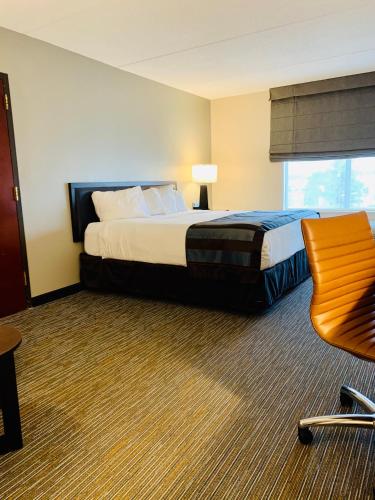 a hotel room with a bed and a chair at Wingate by Wyndham Wilmington in Wilmington