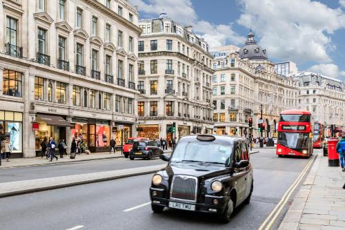 a car driving down a city street with a double decker bus at Oxford Circus Luxury Holiday Let in London