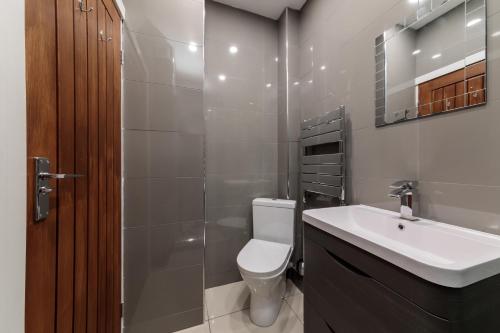 een badkamer met een toilet, een wastafel en een spiegel bij Oxford Circus Luxury Holiday Let in Londen