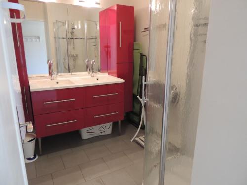 La salle de bains est pourvue d'une armoire rouge et d'un lavabo. dans l'établissement BRUYERE D'ANDAINE, à Bagnoles-de-l'Orne
