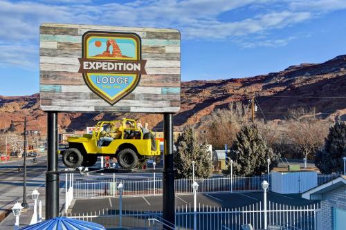 a sign that says expedition lodge with a yellow jeep behind it at Expedition Lodge Moab Arches National Park in Moab