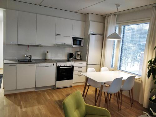 Una cocina con gabinetes blancos y una mesa y sillas. en Siljonportti Apartments with private Sauna, en Rovaniemi
