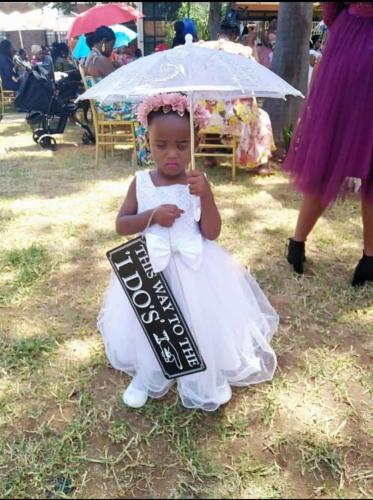 a little girl in a wedding dress holding an umbrella at La Fiato Luxury Lodge in Dalmada AH