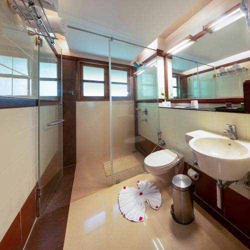 a bathroom with a sink and a toilet and a shower at Greenwoods Resort, Thekkady in Thekkady