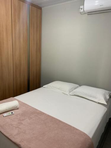 a bedroom with a white bed and a wooden cabinet at Casa Guarda do Embaú in Guarda do Embaú