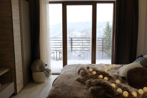 een slaapkamer met een bed en een grote glazen deur bij Ski & Spa Apartment S20 Milmari Resort Kopaonik in Kopaonik