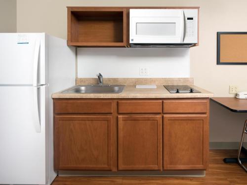 a kitchen with a sink and a microwave at Extended Stay America Select Suites - Kansas City - Stadium in Independence