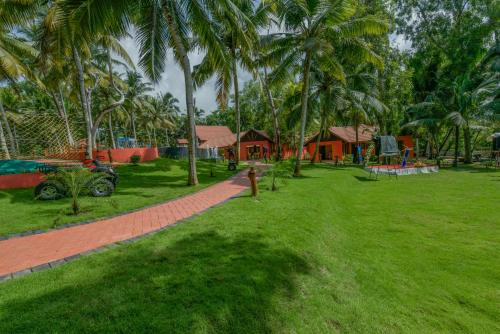 a lawn with palm trees in front of a house at GoGo Land Resort & Adventurous Sports in Pūvār
