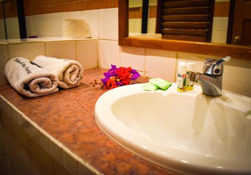 a bathroom sink with towels and flowers on a counter at Grand Eastern Hotel in Labasa