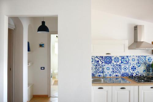 cocina con azulejos azules y blancos en la pared en Appartamento BluMare en Santa Maria Navarrese