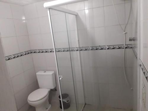 a white bathroom with a toilet and a shower at Pouse Bem in Blumenau