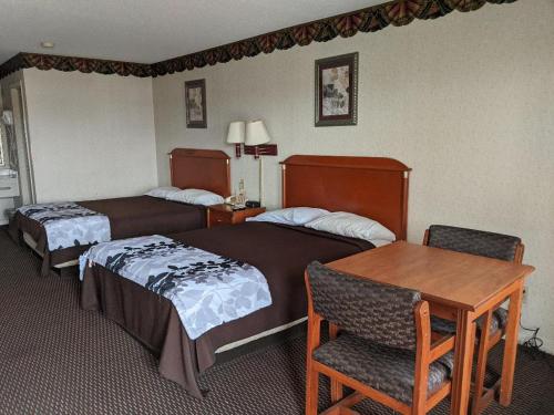 a hotel room with two beds and a table at Key West Inn - Montgomery South in Montgomery