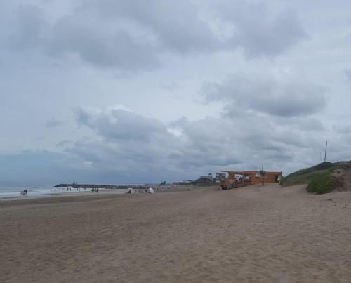 a beach with a house and people on the beach at Cabañas Mangata in Mar de Cobo