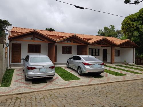 two cars parked in front of a house at Latvia Chalés in Monte Verde