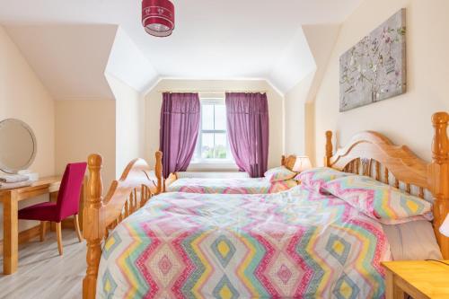 a bedroom with two beds and a desk and a window at Cois Chnoic in Dingle
