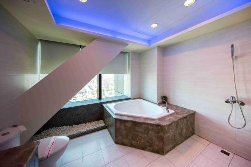 a bathroom with a bath tub and a window at Neo Sky Hotel in Kaohsiung