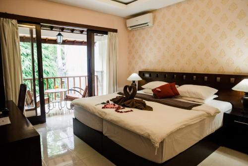 a bedroom with a large bed and a balcony at Desak Putu Putra Hidden in Ubud