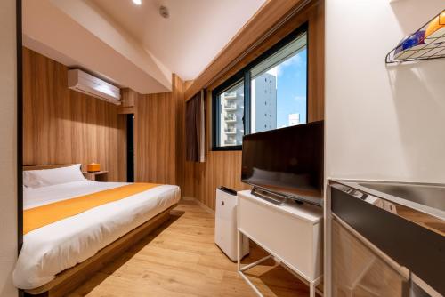 a bedroom with a bed and a flat screen tv at Popway Residence Tennoji in Osaka