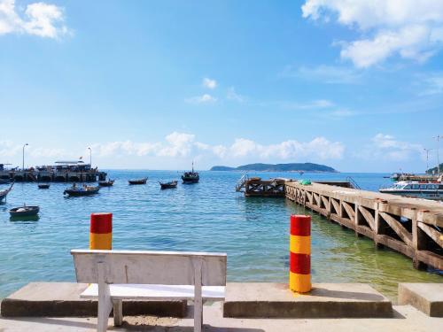 a bench sitting next to a dock with boats in the water at Sunbay Homestay Cu Lao Cham in Tân Hiệp