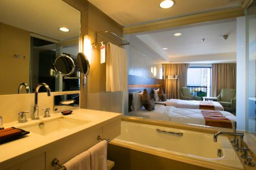 a bathroom with a bed and a tub and a sink at Century Park Hotel in Manila