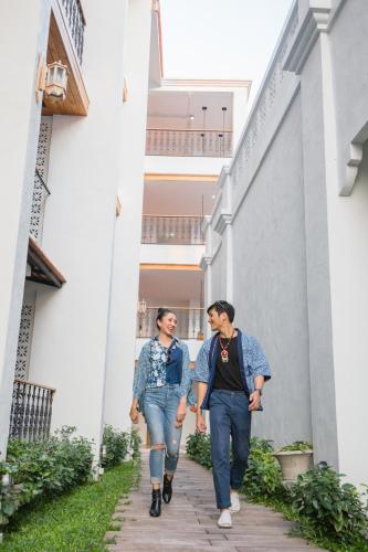 two men are walking down a hallway at Lanna Oriental Hotel in Chiang Mai