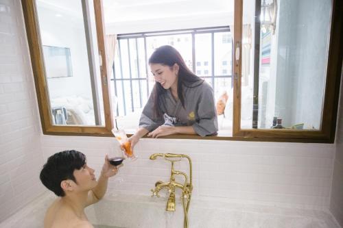 a woman giving a young man a bath in a tub at Lanna Oriental Hotel in Chiang Mai