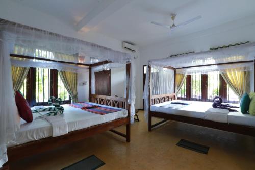 two beds in a room with two windows at Hotel Bay Watch Unawatuna in Unawatuna