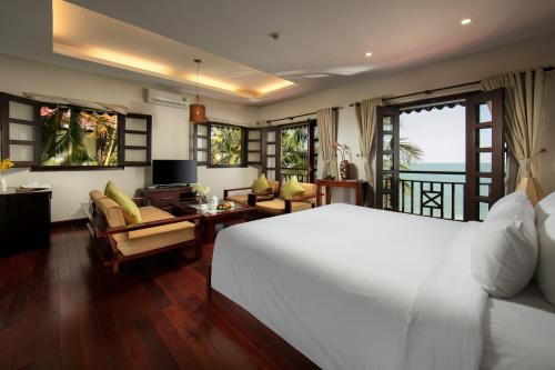 a bedroom with a white bed and a living room at Son Tra Resort & Spa Danang in Da Nang